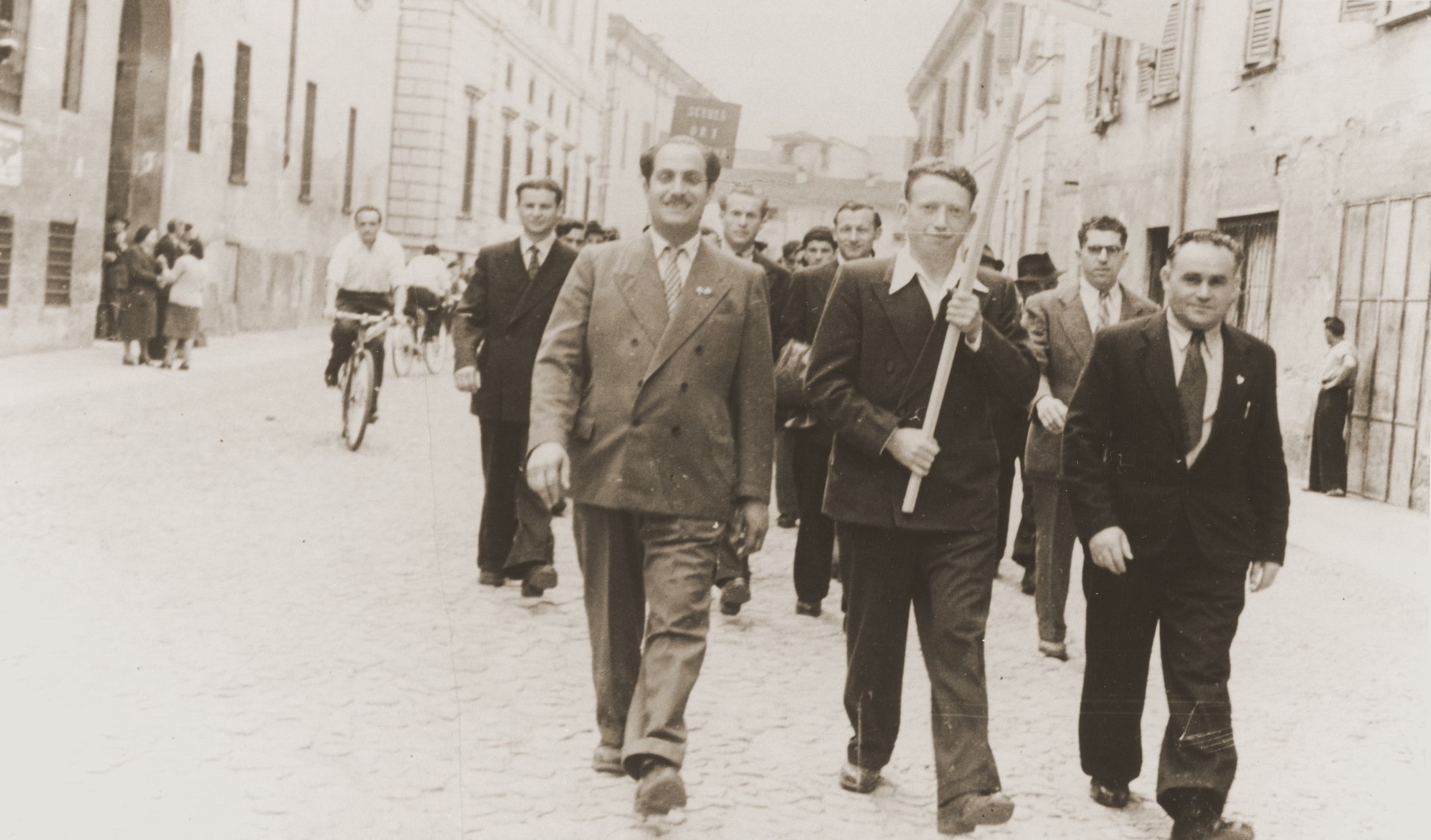 Jewish DPs in the Cremona displaced persons camp take part in a march advocating the creation of a Jewish state.  

Among those pictured is Motel Leikach (front row, right).