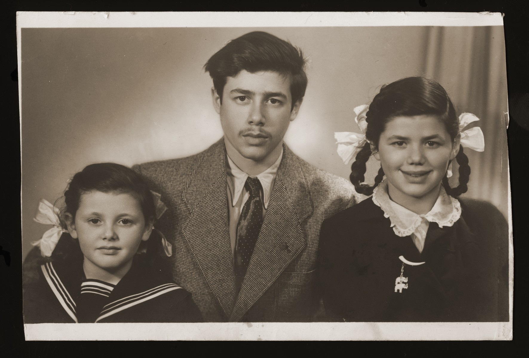 Studio portrait of three Belgian Jewish siblings who survived the war in France.  

Pictured from left to right are: Josephina, Andre, and Lucie Zalc.