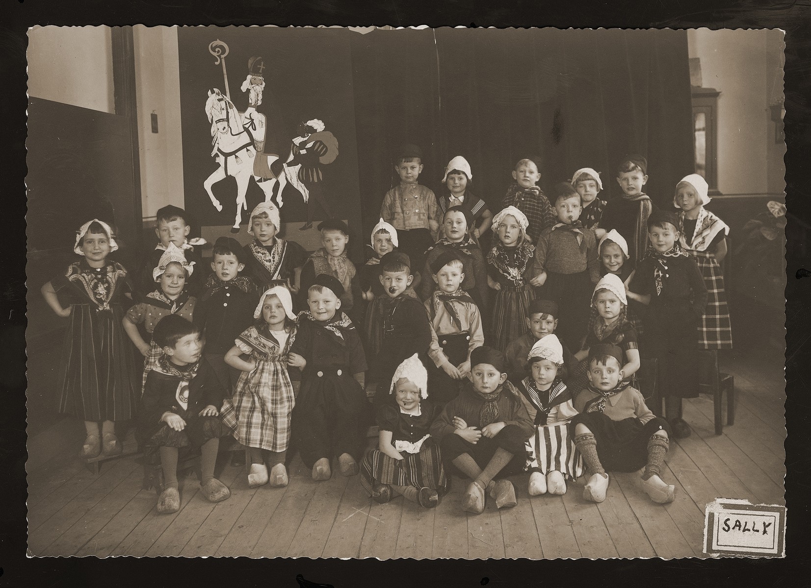 Dutch children pose in traditional costume for a school photo.  Included in the photo are a few Jewish children in hiding.