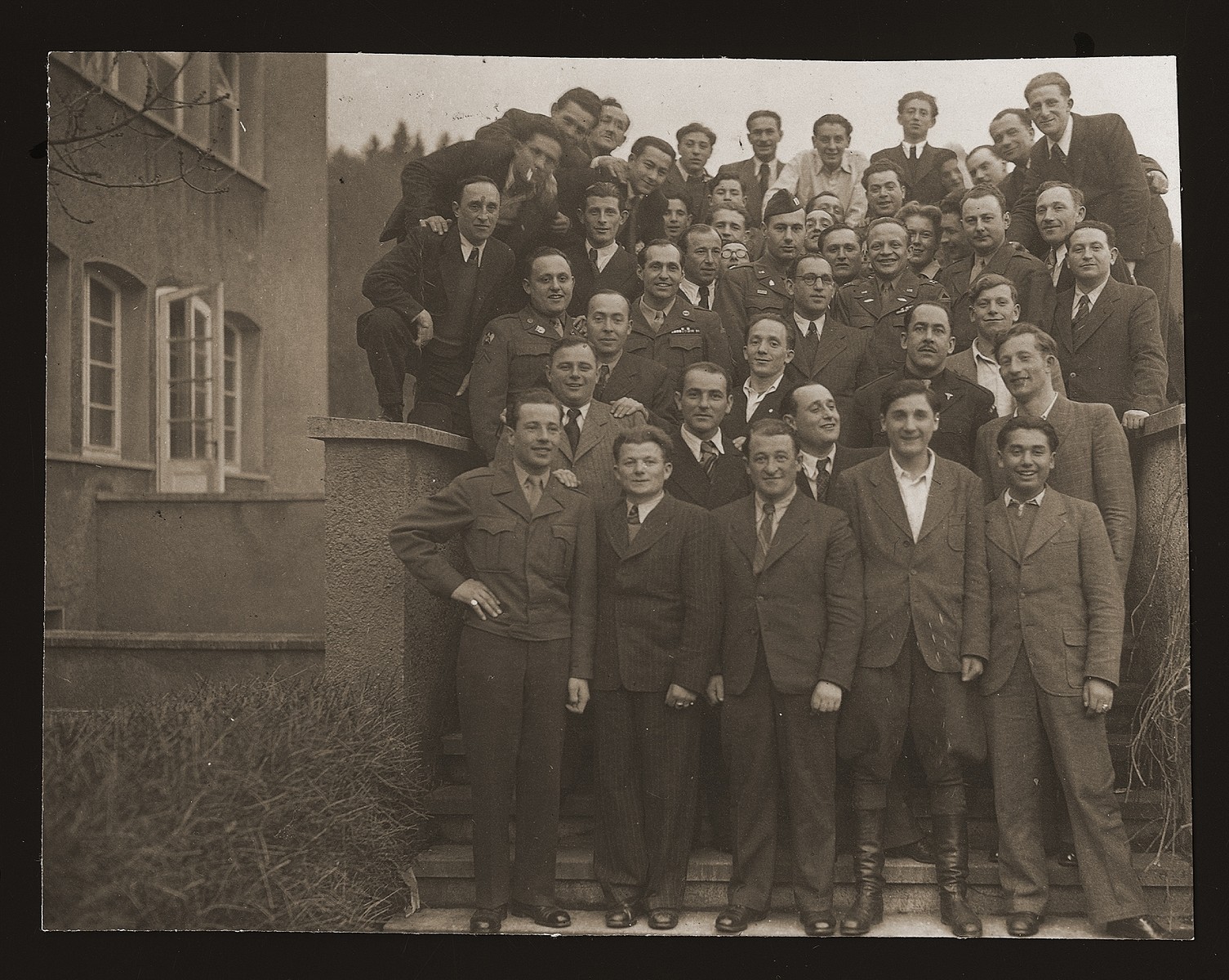 Group portrait of Jewish DPs and American soldiers at the Heidenheim displaced persons camp. 

Leon Kliot (Klott) is standing on the far right, third from the top.  Pictured in the second row from the bottom, on the far left, is Solomon Voicuk from WIlnow, Lithuania