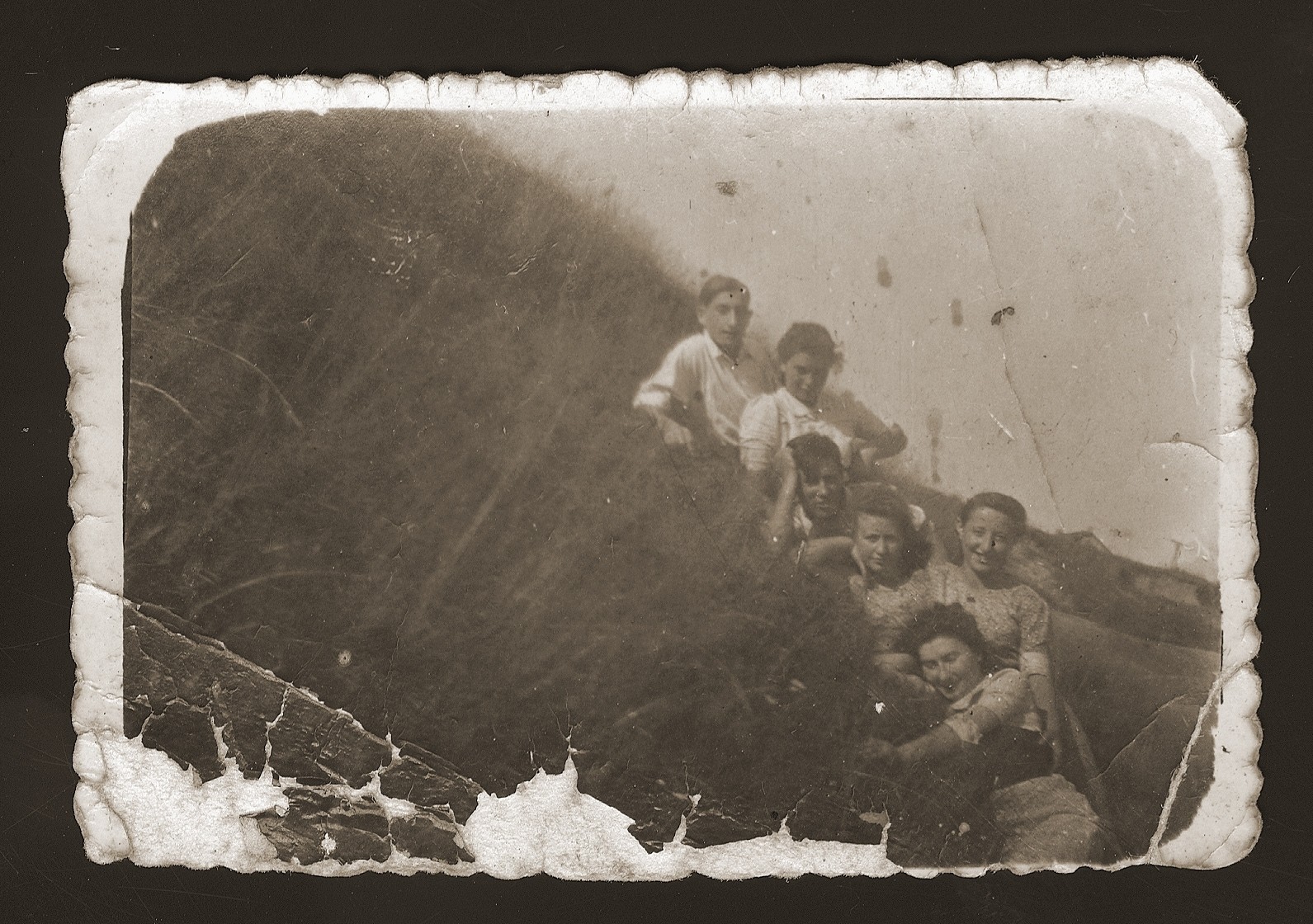 Jewish youth lying on a grassy hilltop in Dabrowa Gornicza, Poland.

Among those pictured are Moniek Rozen (first from the left) and Sabina Szeps.  Szeps gave this photo to Rozen during their imprisonment in the Gruenberg labor camp.