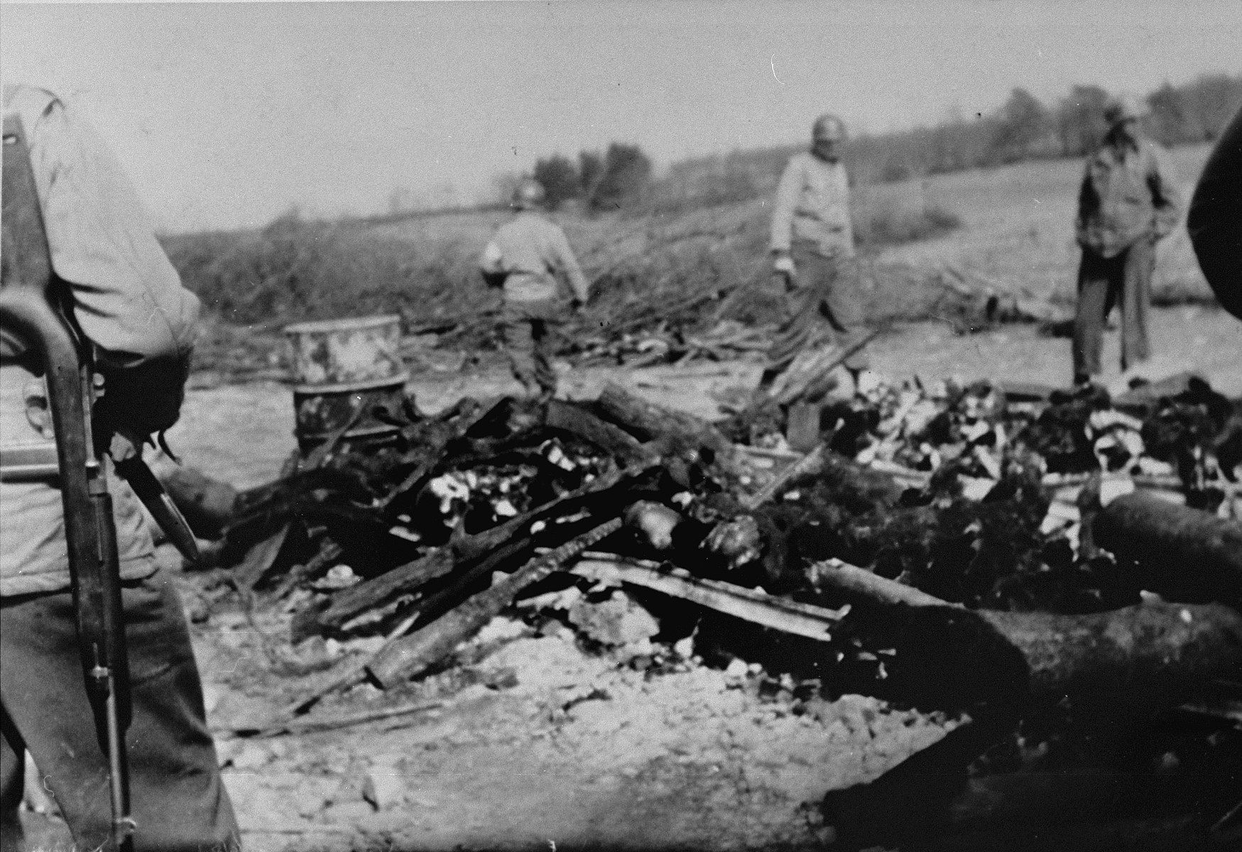 While on an inspection tour of the newly liberated Ohrdruf concentration camp, American soldiers view the charred remains of prisoners that were burned upon a section of railroad track during the evacuation of the camp.