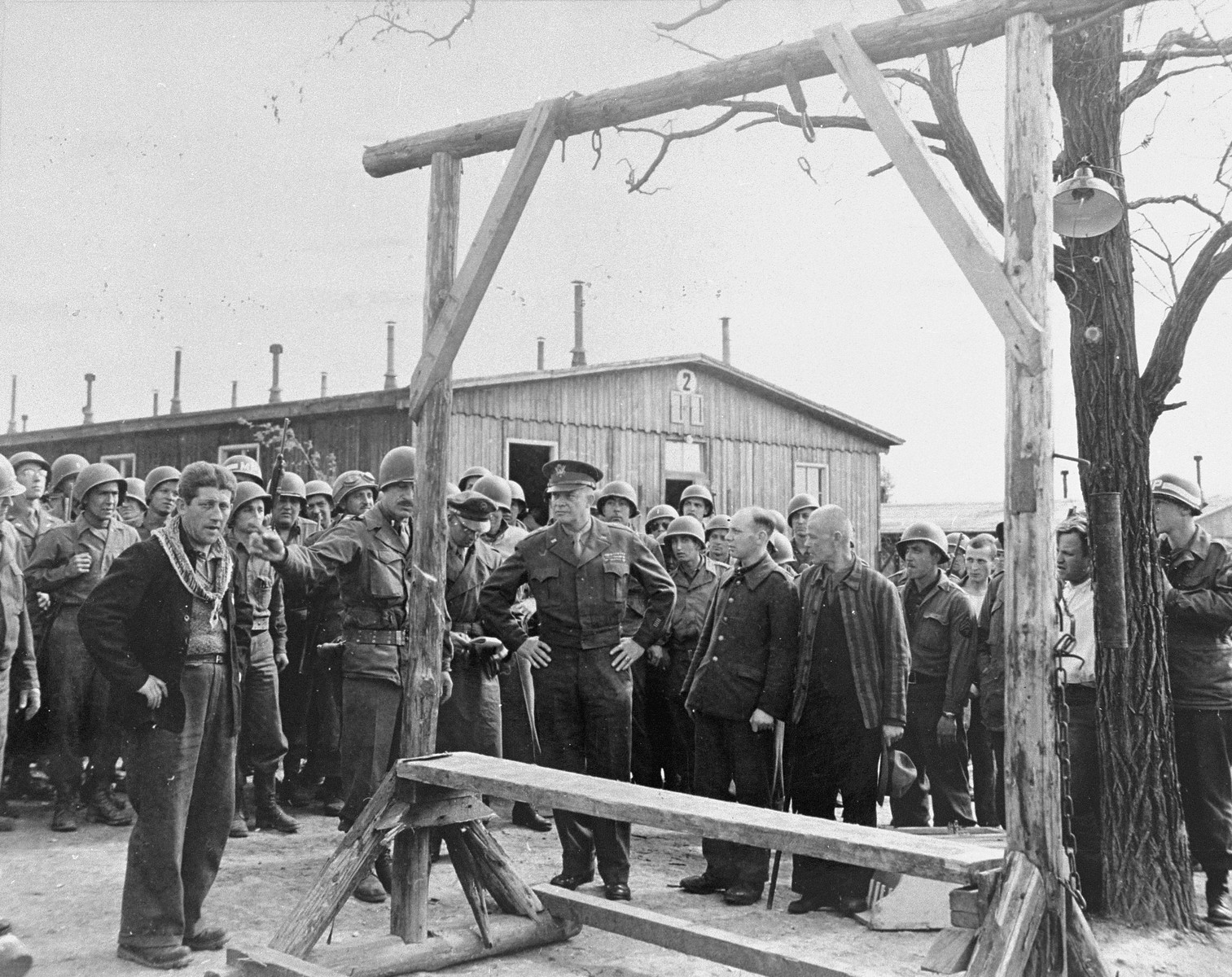 During an official tour of the newly liberated Ohrdruf concentration camp, an Austrian Jewish survivor describes to General Dwight Eisenhower and the members of his entourage the use of the gallows in the camp.

Among those pictured is Jules Grad, correspondent for the U.S. Army newspaper "Stars and Stripes" (on the right).