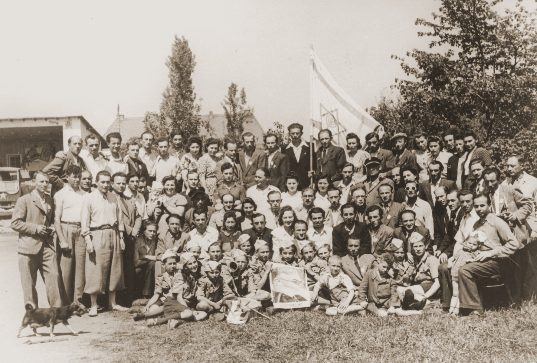 Group portrait of members of Betar Zionist youth movement in Neu Freimann displaced persons camp holding a Zionist flag and portrait of Zev Jabotinsky.

Among those pictured in the second row are the pricipal Mrs. Spektor and Moshe Blautal.