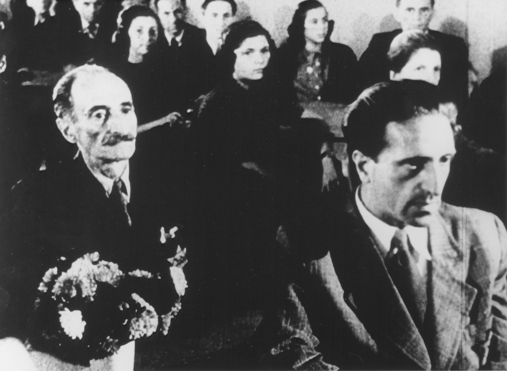STILL PHOTOGRAPH FROM THE NAZI PROPAGANDA FILM, "Der Fuehrer Schenkt den Juden eine Stadt" [The Fuehrer gives the Jews a City].  Jews watching a performance in the Theresienstadt ghetto.

The man on the right is Pavel Haas, who is actually listening to his Study for Strings performed by the Ghetto Orchestra