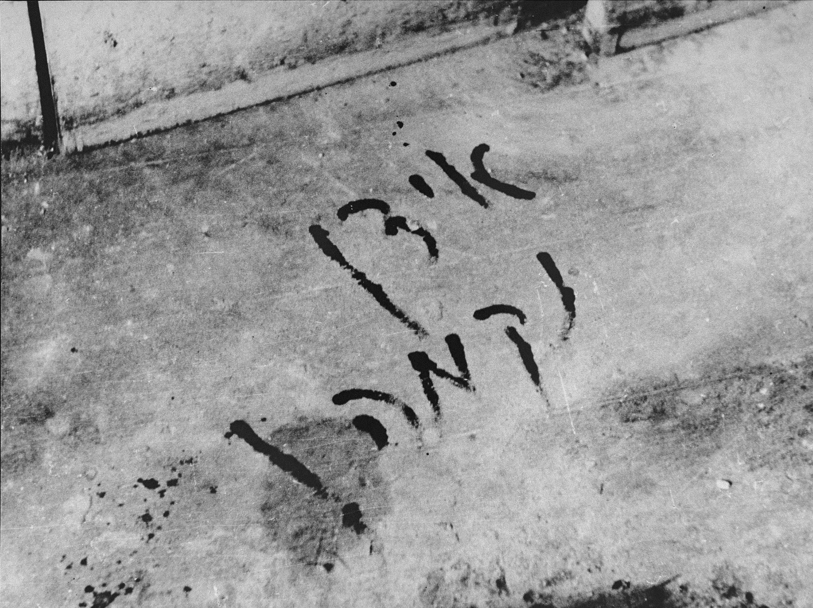 The Yiddish words, "Jews Revenge!" scrawled in blood on the apartment floor of a Jew murdered in the Slobodka pogrom.  [oversized photo]