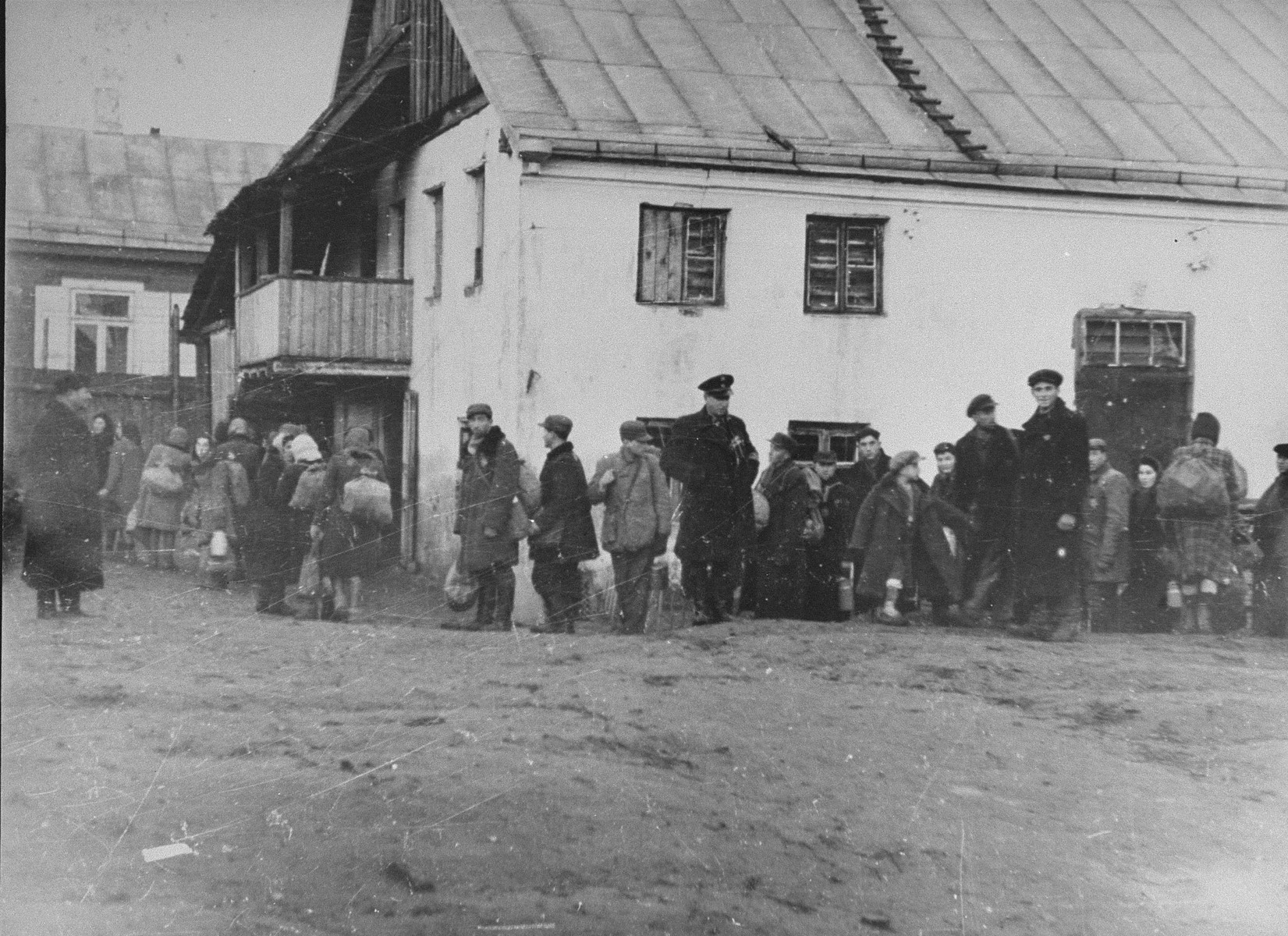 A group of Jews return to the ghetto after forced labor on the outside. Here, they line-up to be searched. Jewish police stand among them.