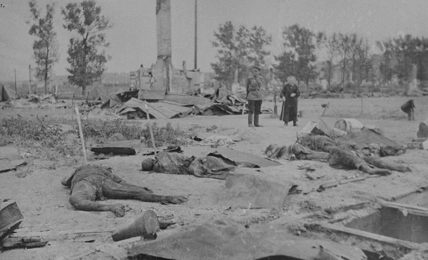 A Russian officer and an elderly woman view the devastation that resulted from the razing of the Kovno ghetto.  Charred human remains are strewn among the rubble.