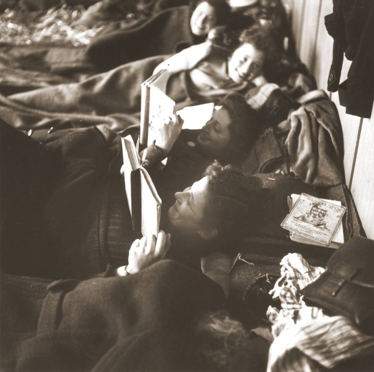 Jewish women rescued from Theresienstadt read while resting on their beds of straw in the Hadwigschulhaus in St. Gallen.