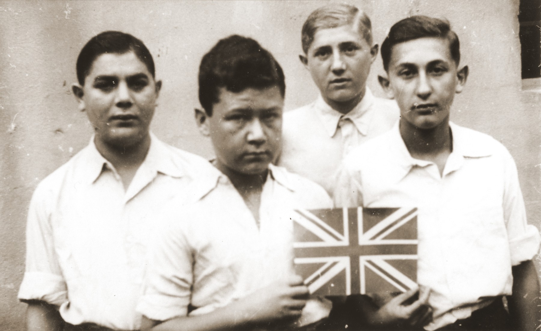 Four members of the orphans transport pose with a Union Jack soon after their arrival in England.

Among those pictured are Polek Gastfreund (right); Jerry Herszberg (second from the left); and Felix Berger (left).