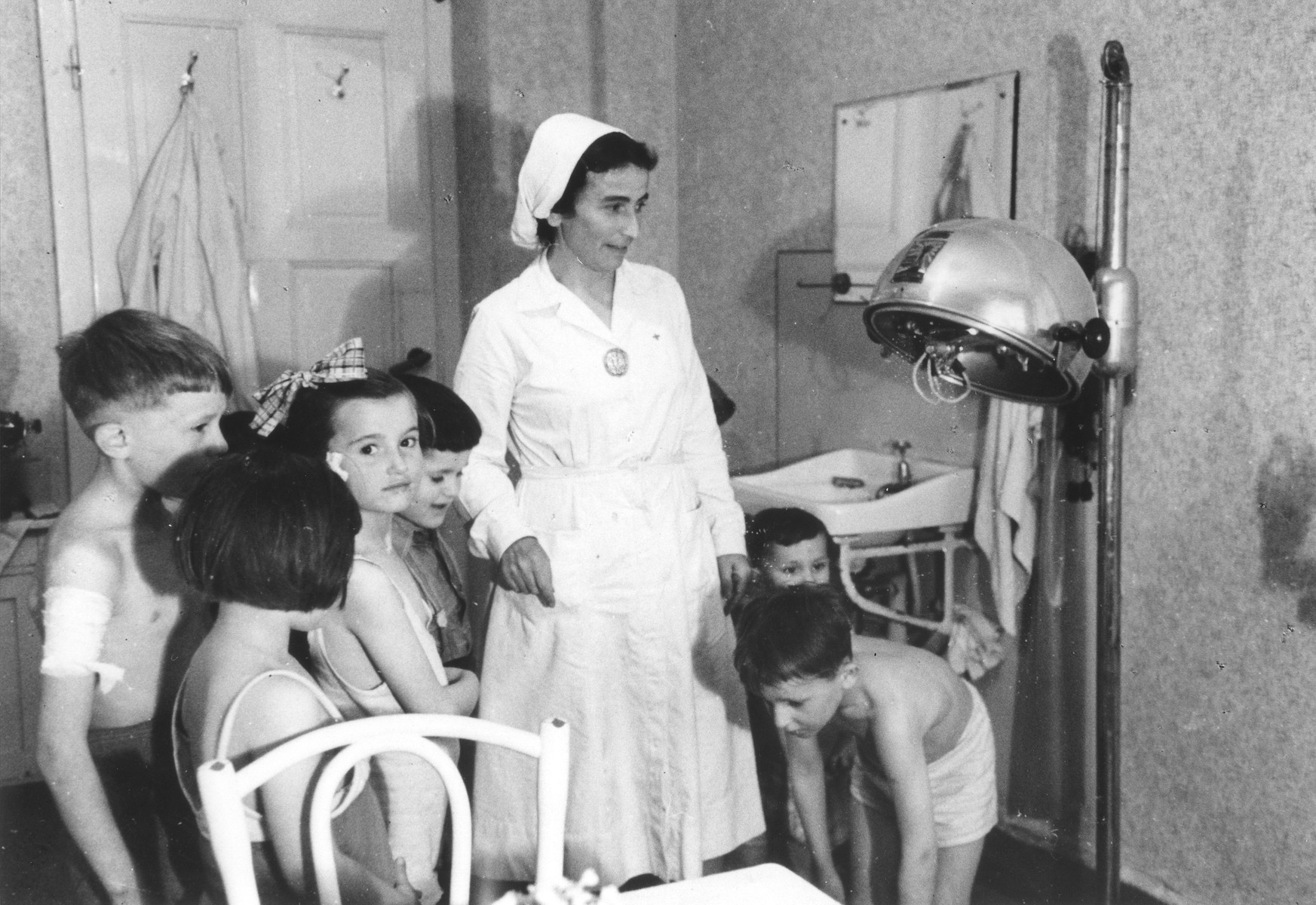 A nurse administers artificial sunlight therapy to undernourished children in the Bad Schallerbach children's home.