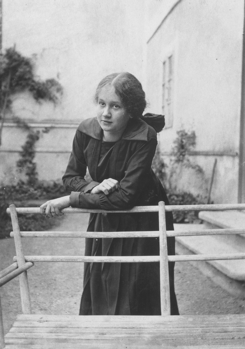 A teenage Jewish girl poses outside her home leaning on the back of a wooden bench.

Pictured is Irenka Huber.  Irenka, the sister of Eliska (Huberova) Deutschova, survived WWII in hiding in Hungary.