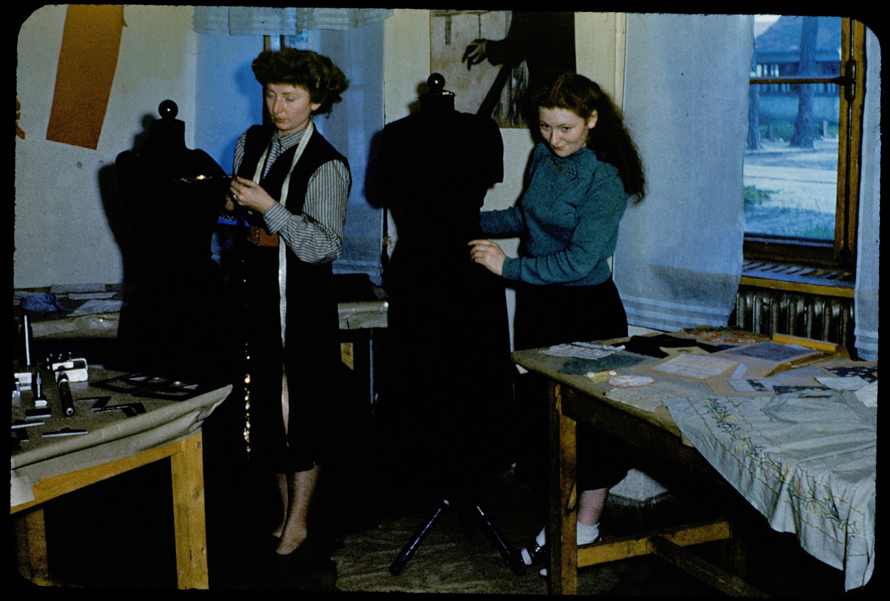Women learn dressmaking at an ORT vocational training school in the Foehrenwald displaced persons camp.

Standing on the right is Brenda Maryles (nee Soroka) and the woman on the left is the instructor.