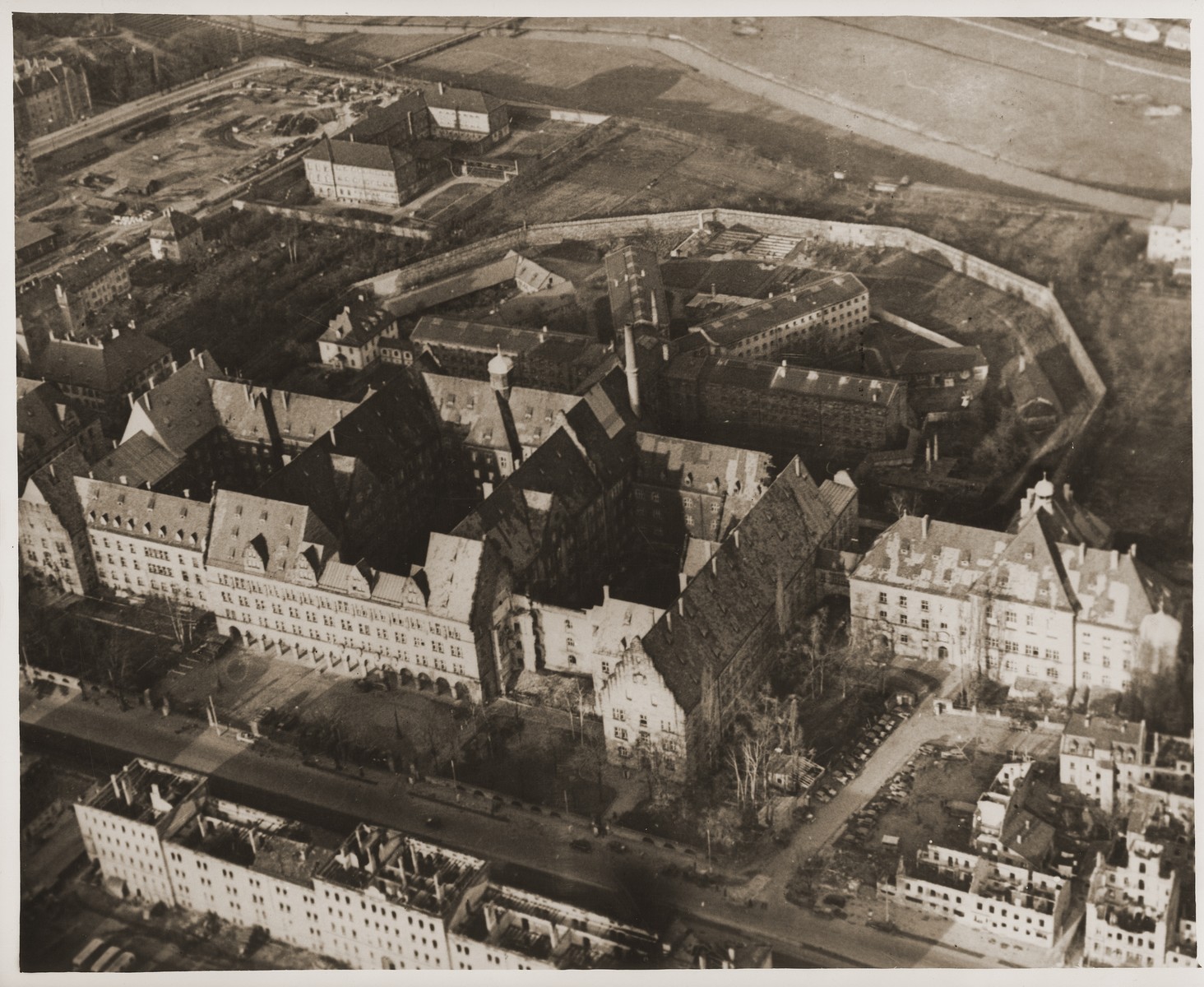 Aerial view of the Nuremberg Palace of Justice and prison, where the war crimes trial of the International Military Tribunal was held and its defendants incarcerated.  

In the foreground is the Palace of Justice.  The structure on the right that is connected to the the main building by a passageway, is where the actual courtroom is located.  The main part of the Palace of Justice houses the offices of those working on the IMT.  In the background are the four wings of the Nuremberg prison.  The IMT defendants are housed in the far right wing; the witnesses in the left wing; and other prisoners in the two center wings.