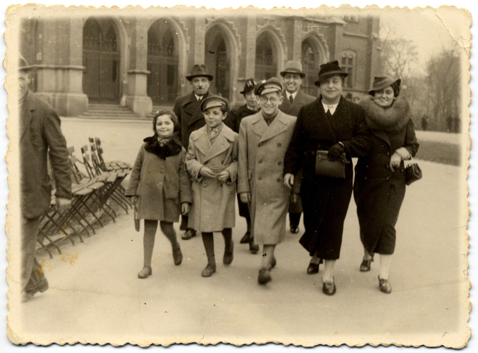 Group portrait of adults and children walking in front of the Jagiellonski University in Krakow. 

Pictured in the front row, from left to right, are Dola and Josef Horowitz, unknown, Esther? Zehnwirth and Rozia Lesser.  In the back row, from left to right, are Chaim and Fela Horowitz, and Fela's brother, Monek Lesser who had just graduated from the Medical Faculty of the Jagiellonski University.