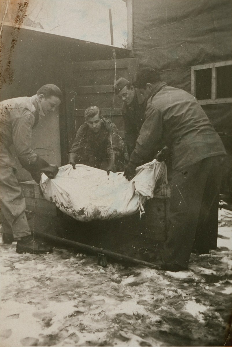 American troops loadi a corpse into a coffin at Ebensee.