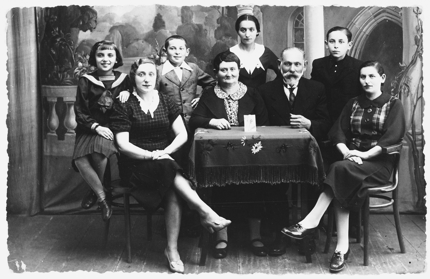 Prewar portrait of the Zisman family in Zelow, Poland.

Pictured seated in front, second from the right, is Zysman Kifer.  Also in the front row (left to right) are (probably) Chana Faiga (daughter of Zysman), Hena Brand (sister-in-law to Zysman and a midwife), and Hinda (daughter of Zysman,seated on the far right).  Pictured in the back row (left to right) are Esther Gitel Yacobovitch, her brother Avraham Shumel Yacobovitch, [unidentified], and probably Shlomo Yacobovitch.

Hena was well known for serving as a midwife to lower income families.  She did not charge them a fee, and often brought clothing for the newborns and their families.

Zysman Kifer died in 1941 in Chelmno.  Esther, Avraham, and Hinda also perished in Chelmno.  Shlomo survived.