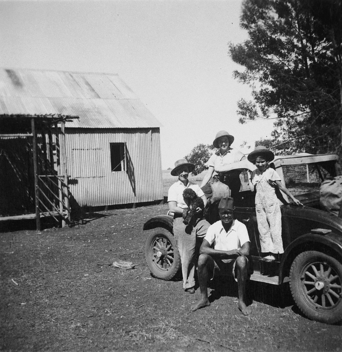 Members of a Jewish refugee family pose with an African assistant in front of their car on their farm in Kenya.

Pictured are members of the Zweig family.  Stefanie Zweig is on the right.