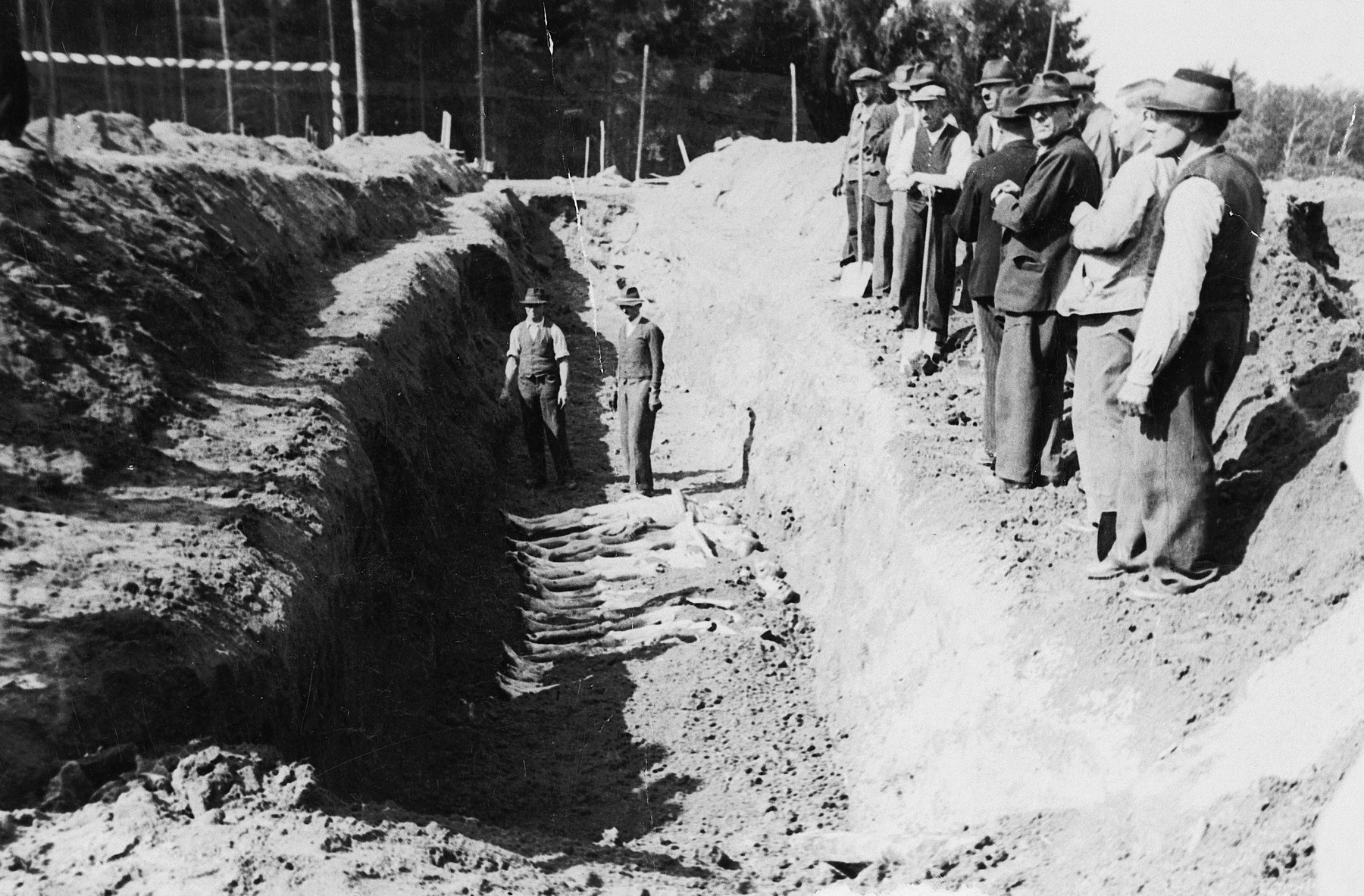 Austrian civilians are forced to bury corpses in a mass grave in the Mauthausen concentration camp.