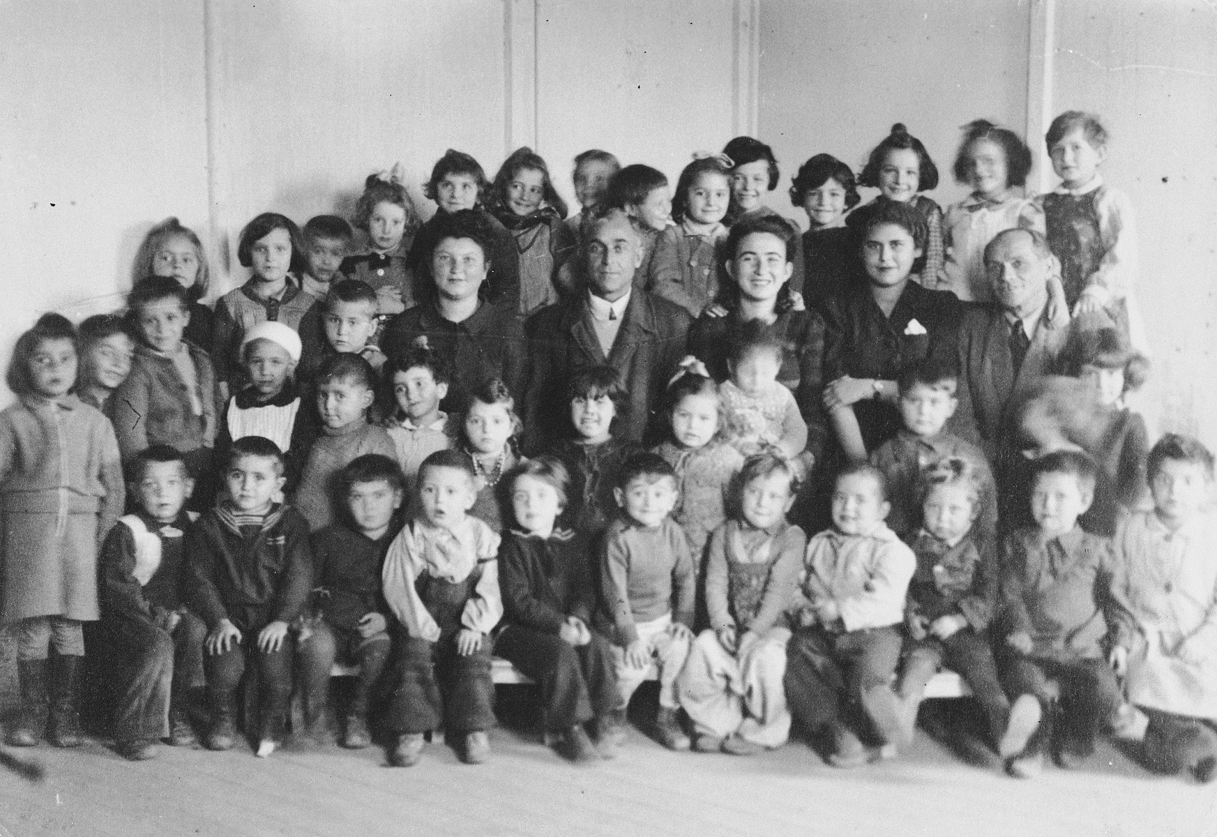 Teachers and young children in the elementary school in the Ainring displaced persons camp.

Among those pictured is the teacher, Sara Michlowitz (Muschel), center row, third from the right.  Also pictured is Rachel Yudkowitz (seventh child standing from the left , wearing a bow in her hair).