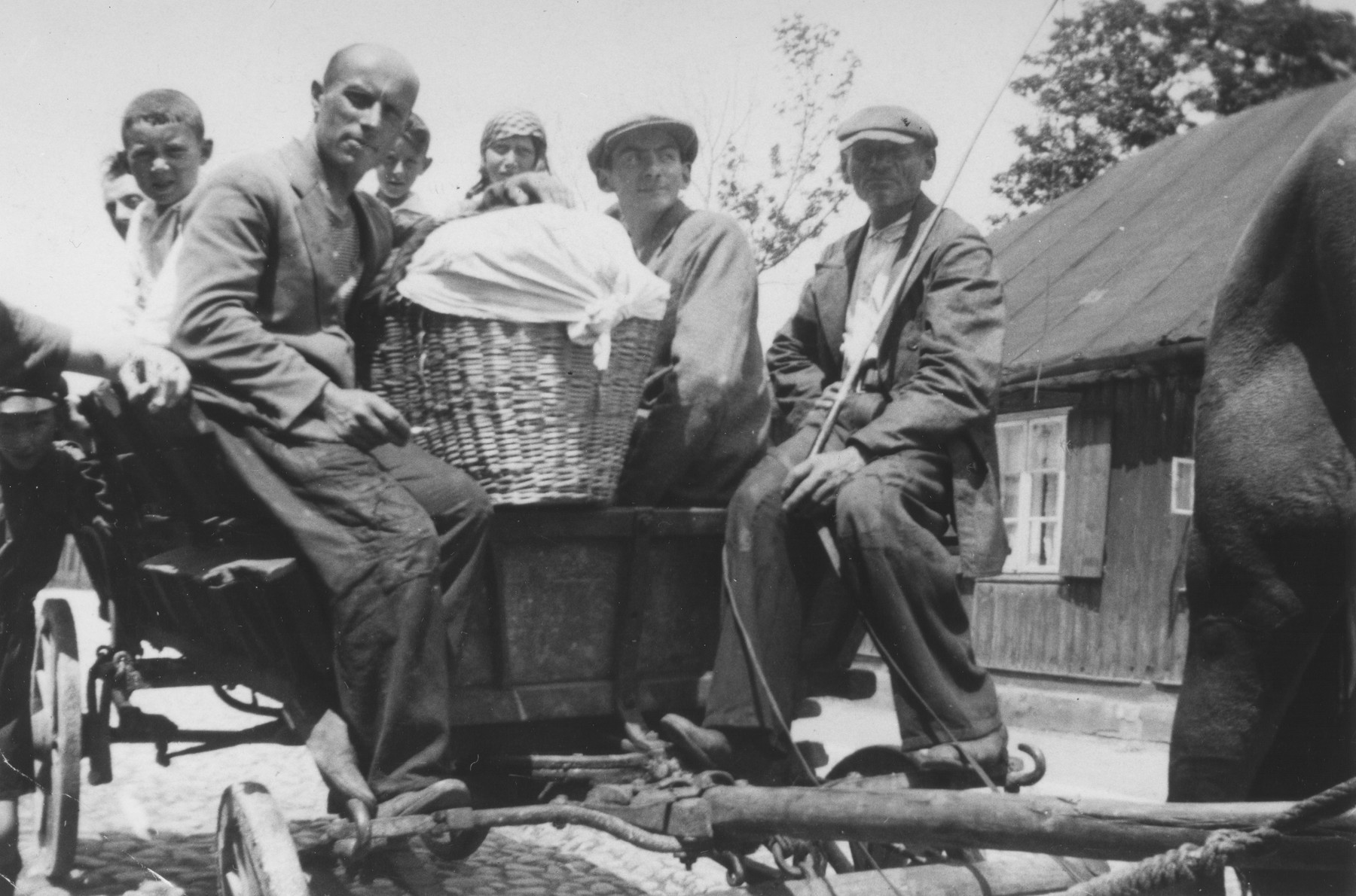 A group of Jews rides on the back of a horse-drawn wagon in Piotrkow Trybunalski, Poland.

The group is on their way to a neighboring town where the man with the basket will sell his wares.

Among those pictured are Reuven Fish, Shaya Wolrajch, Hersh Lieb Wolrajch, Chiemic and Wolf.