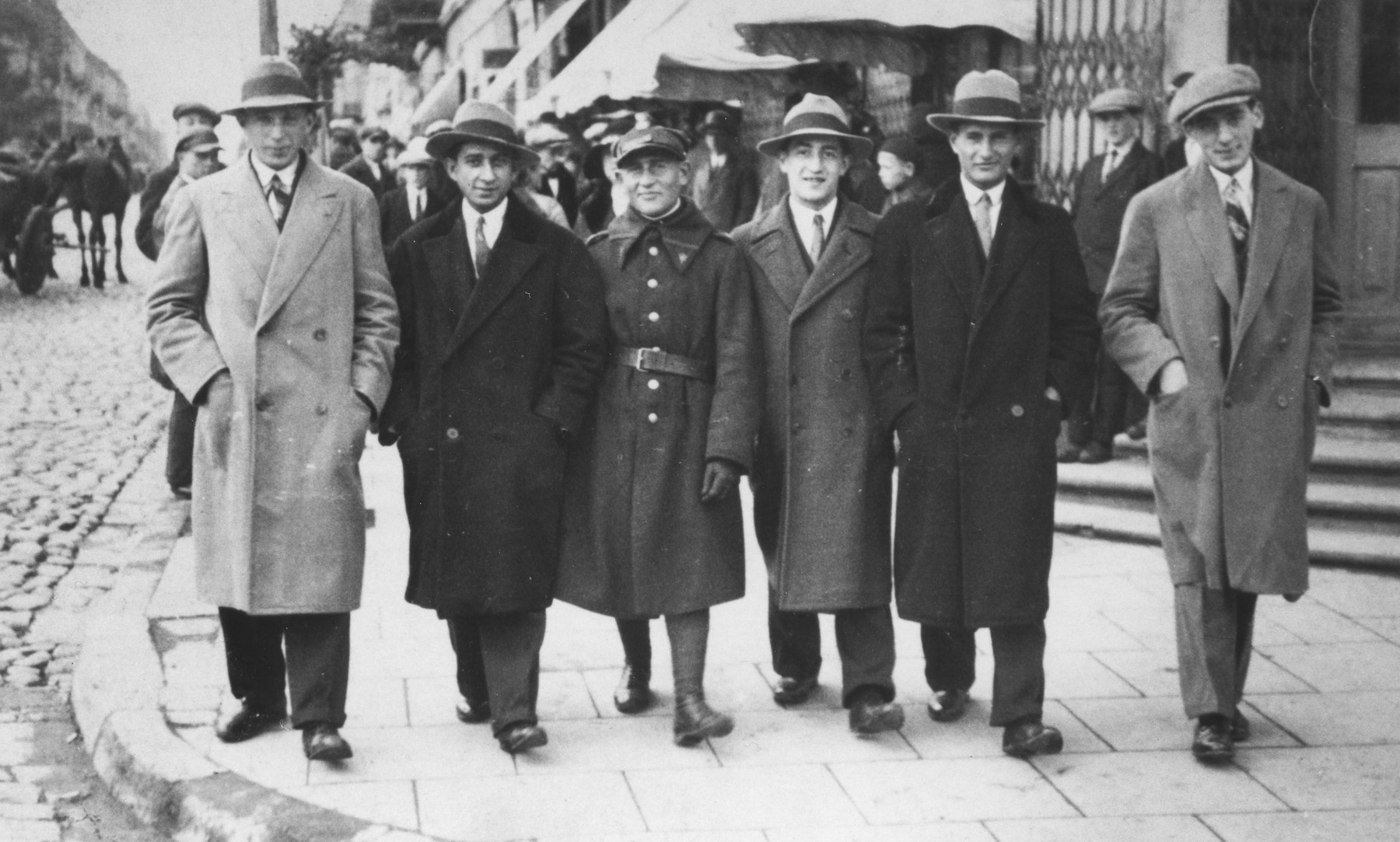 A group of Jewish friends walk along the main street of Piotrkow Trybunalski.

Pictured from left to right are: Weinberg, Schmel Lieberman, Itchak Rosencweig, Schmuel David Horn, and Boruch Hersh Weinberg.