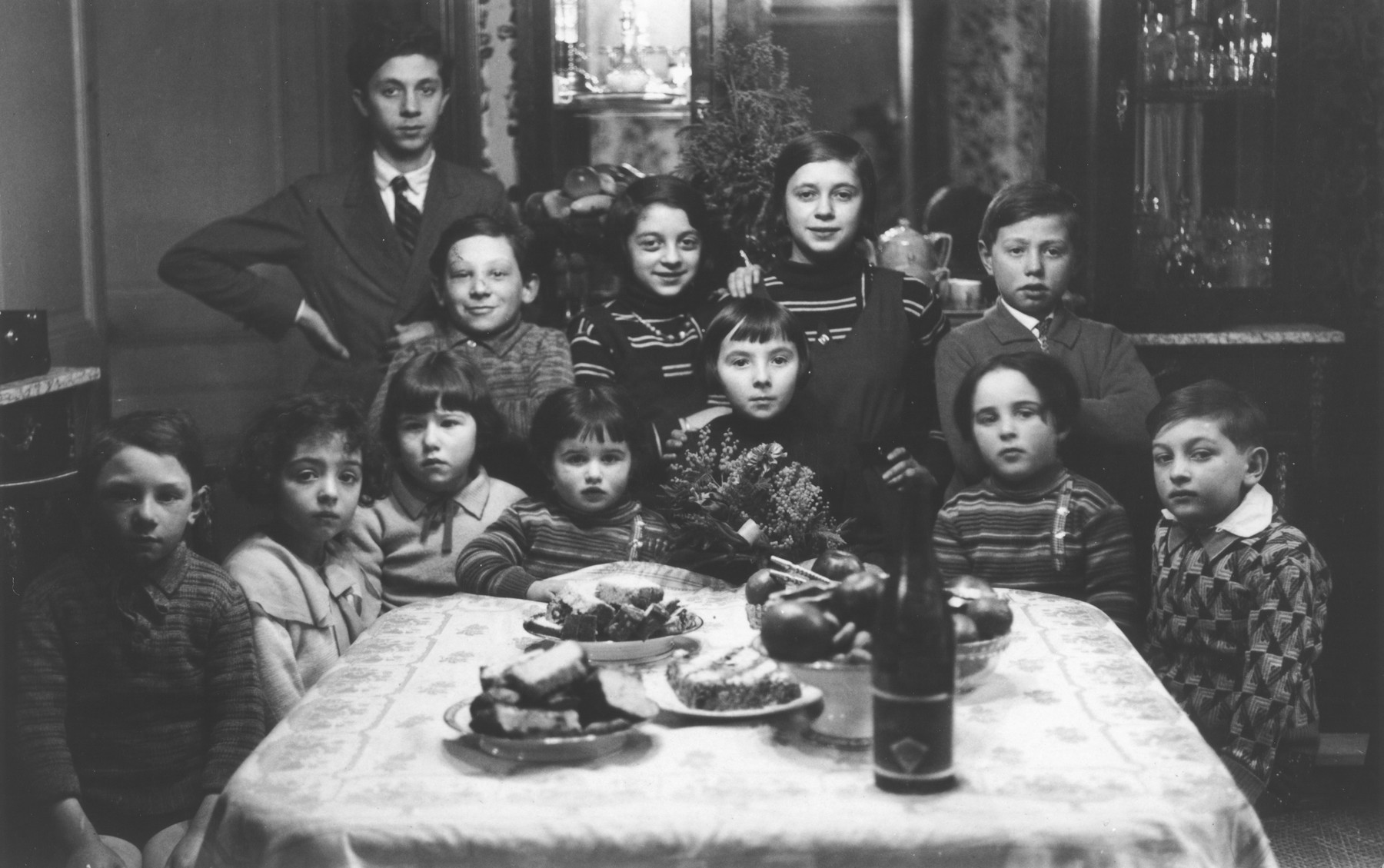 Group portrait of Jewish children gathered around a table at a birthday party in Paris.

Among those pictured are Aba Sztern (second row far right) and his sister Catherine (front row, third from the left).