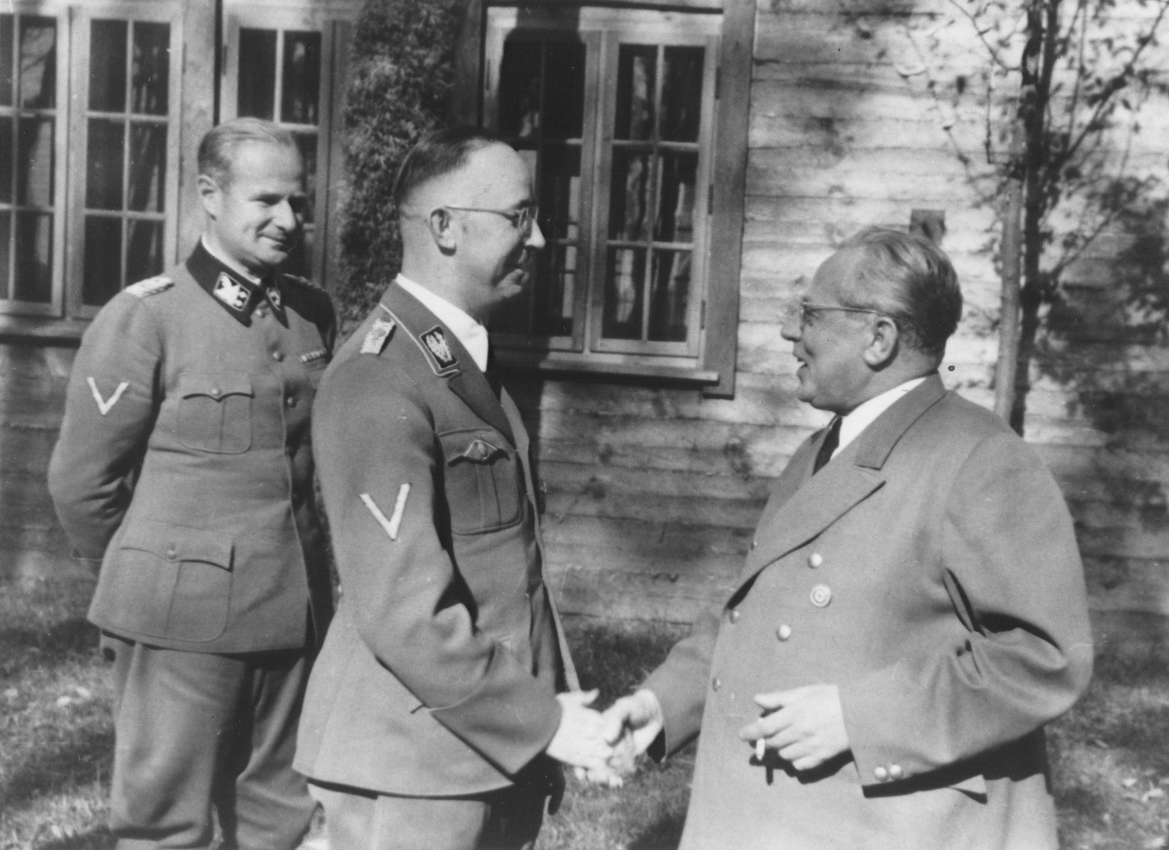 Reichsfuehrer-SS Heinrich Himmler shakes hands with photographer Heinrich Hoffmann outside a cabin.

Pictured from left to right are: Karl Wolff, Himmler and Heinrich Hoffmann.