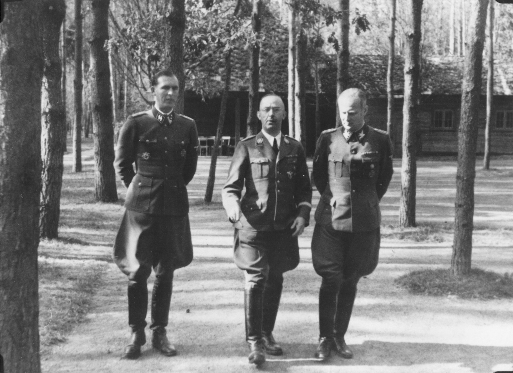 Reichsfuehrer-SS Heinrich Himmler strolls with two other SS officials [probably at Wolfsschanze (Wolf's Lair), Hitler's field headquarters in Rastenburg, East Prussia]. 

Pictured from left to right are: Richard Schulze-Kossens, Himmler and Karl Wolff.