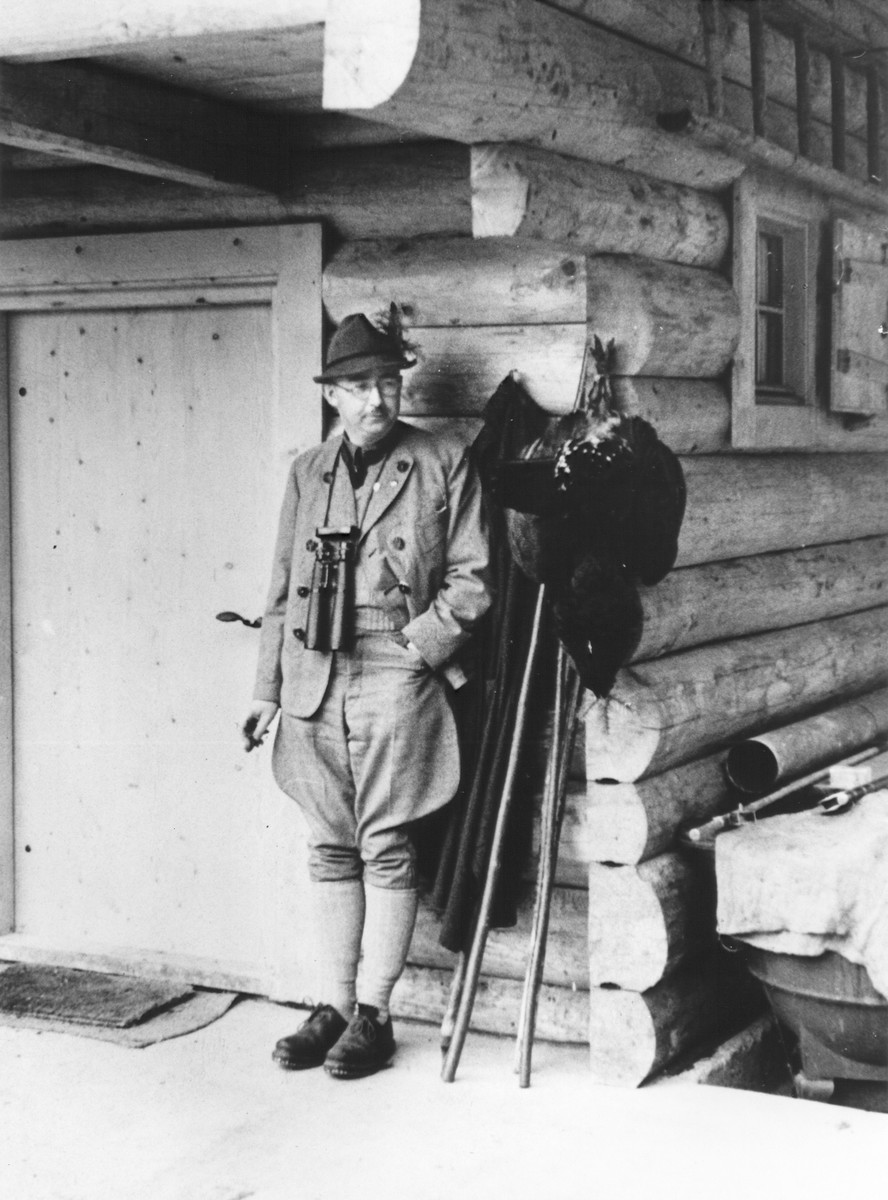 Heinrich Himmler poses in front of a hunting lodge.