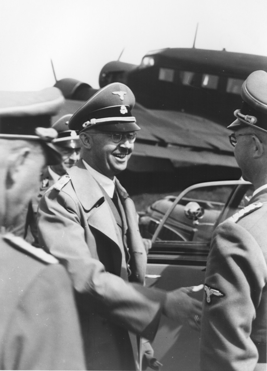 Reichsfuehrer-SS Heinrich Himmler shaking hands with Hermann Bartels at the airport in Paderborn, Germany.

Also pictured behind Himmler is SS-Gruppenfuehrer Siegfried Taubert.