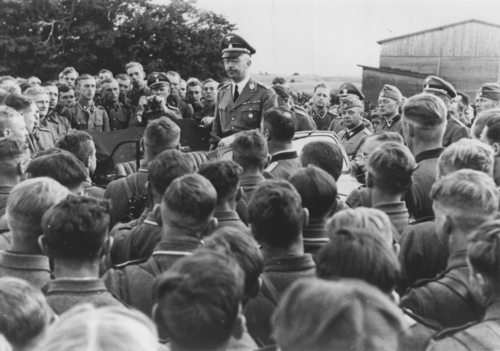 Reichsfuehrer-SS Heinrich Himmler addresses a group of soldiers in a cavalry regiment of the Waffen SS in the eastern territories.

Among those pictured are Kurt Knoblauch (standing near car) and Himmler's boyguard, Josef Kiermaier (holding a camera).