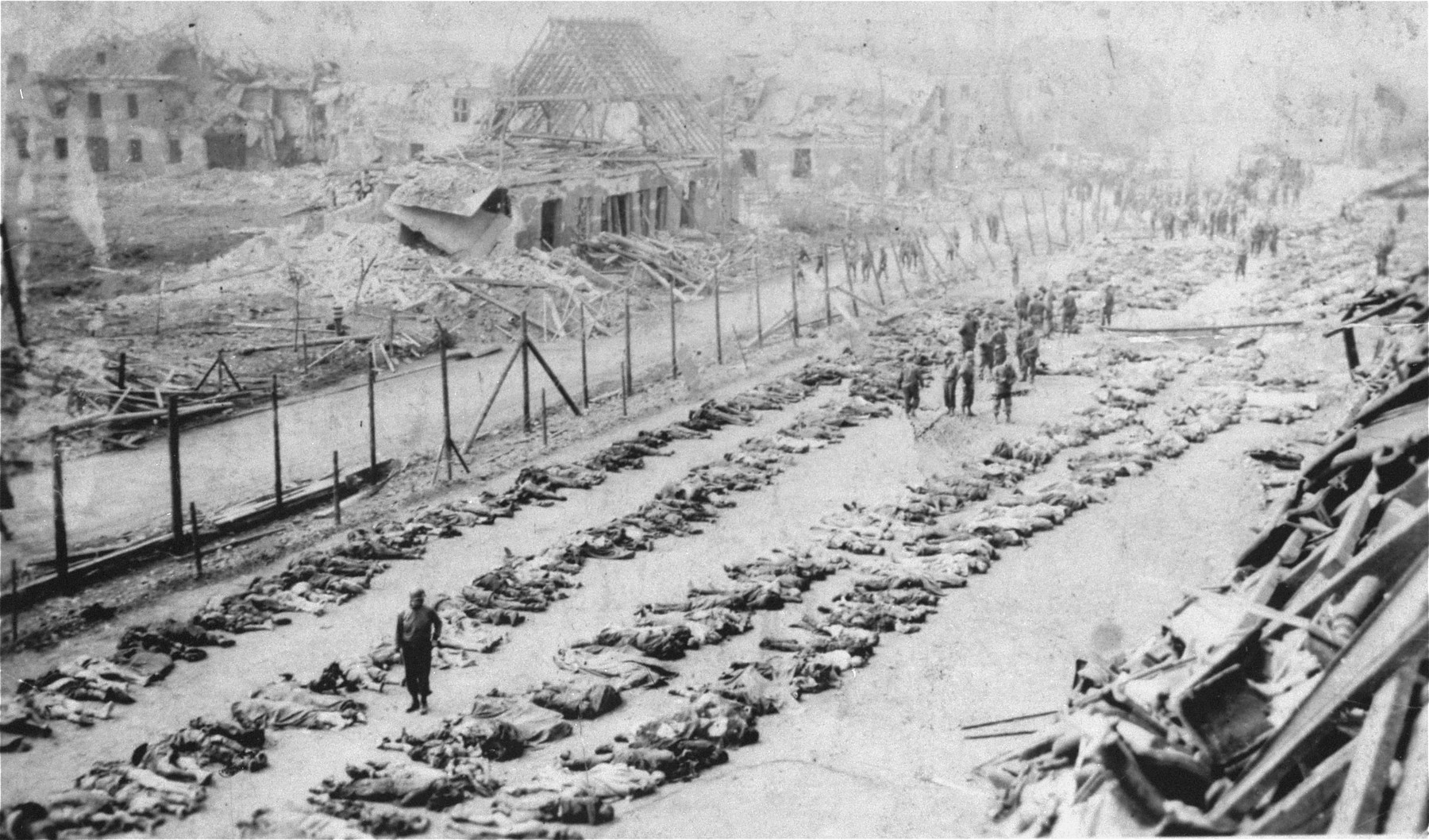 American soldiers walk among rows of corpses in the Nordhausen