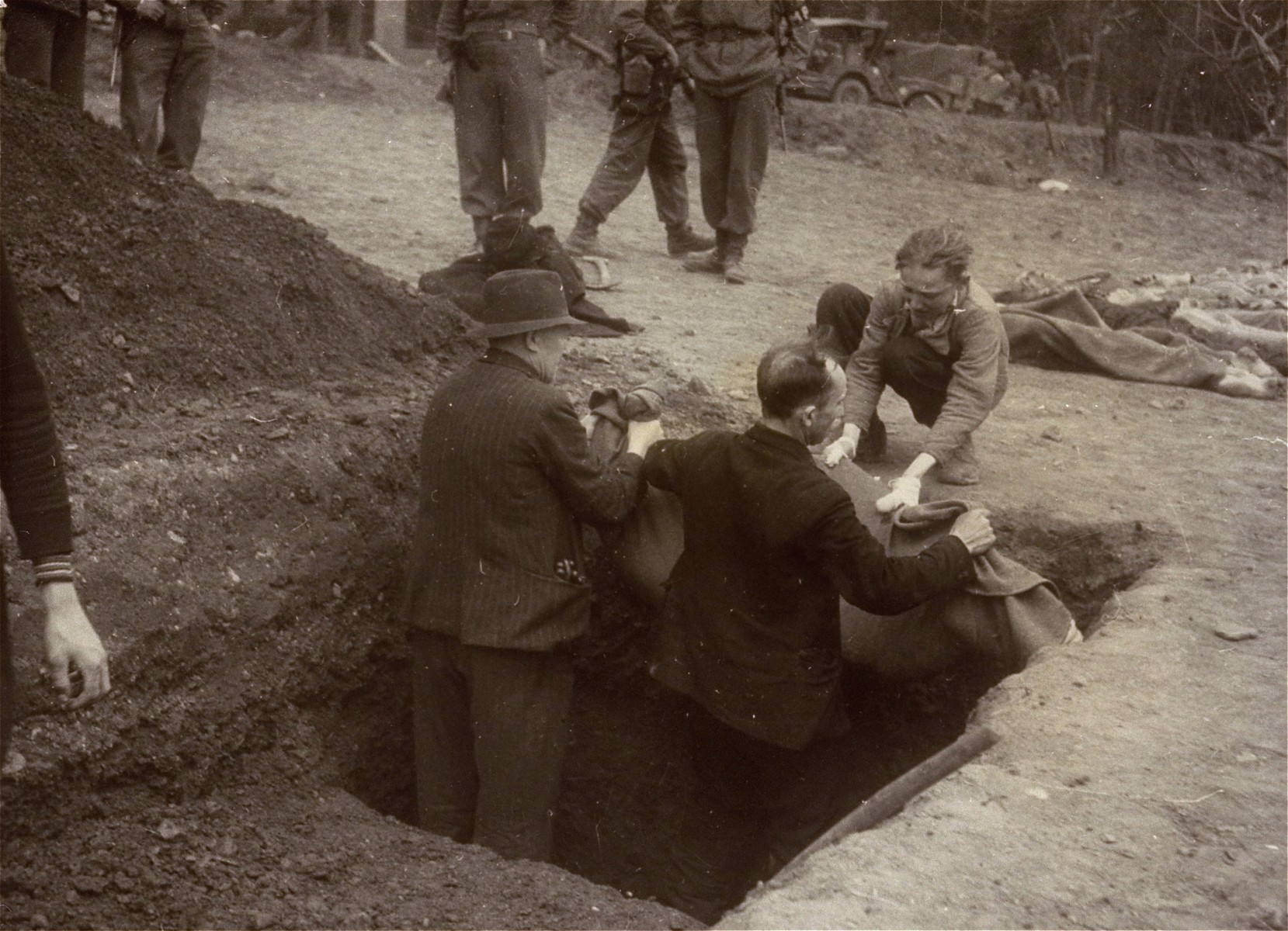 A Polish man, Walter Kallaur and his son, Michael, bury the boy's grandmother, Elizabeth Kallaur who died in the Nordhausen concentration camp, as American soldiers look on.  

Elizabeth's head had been severed shortly before liberation.  The Kallaur family was sent to Nordhausen as punishment for helping Jews in the Pinsk region.

These survivors would not allow the Germans to touch their dead, even after Colonel D.B. Hardin ordered the civilian population of the town of Nordhausen to bury the corpses of prisoners found in the Nordhausen concentration camp.