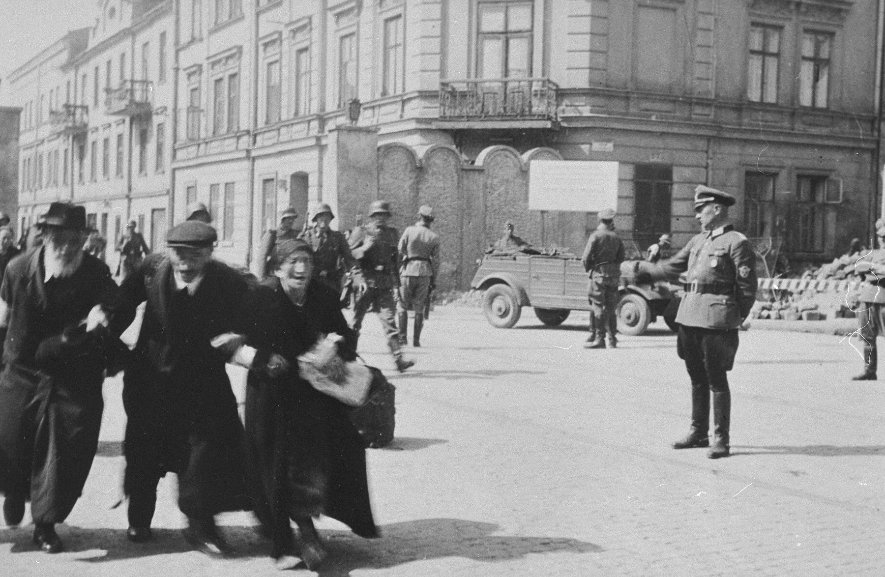 Three elderly Jews walk arm-in-arm through the streets of Krakow during the final liquidation action of the ghetto.