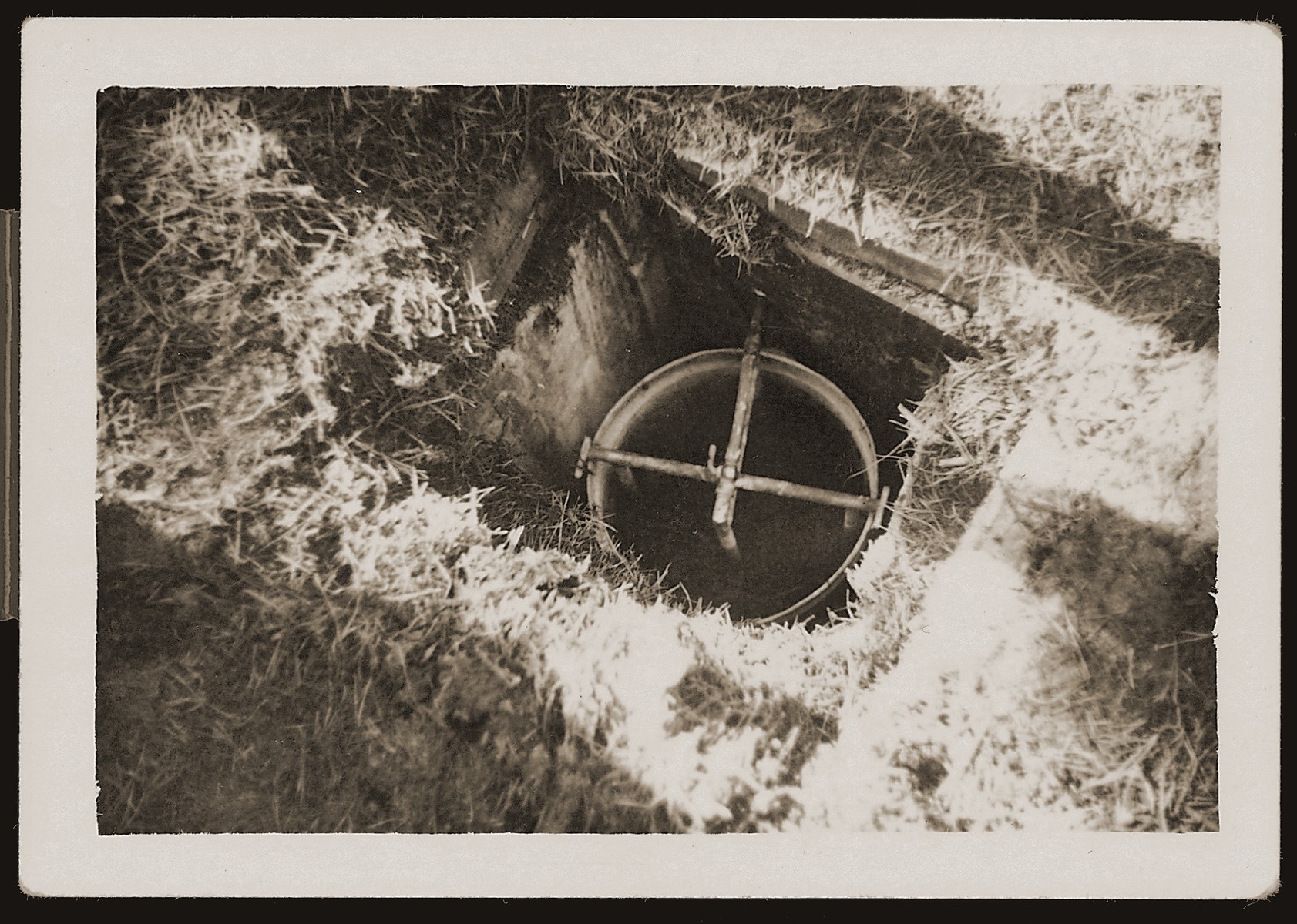 A vent that was installed in a bunker that served as a hiding place for Dutch Jews in the Eibergen region in 1942-1943.  The bunker was discovered by the Germans one day before this photograph was taken.

The bunker was, in actuality, a prefabricated hut that was ordered by two Jewish brothers, Abraham and Herman Maas from Eibergen.  It was delivered in sections to a site in the Hoones Forest outside Eibergen.  The Maas brothers got permission from the manager of the privately-owned forest to build a subterranean hiding place for themselves.  Two sympathetic non-Jews conveyed the materials, dug the hole and assembled the shelter, which had two rooms and a crude stove.  Initially, only the brothers hid there, but as times grew more desperate, 23 Jews were concealed in the bunker.  On March 27, 1943 a Dutch informer led Germans to the site.  All 23 were arrested and sent to Westerbork.  From there they were deported to Sobibor and killed.  After the war the informer was identified as E. Heijink and tried as a collaborator.

The photographer was a Dutchman, who was ordered to take pictures of the bunker the day after the Jews were captured.  He made an extra set of prints, which he kept secretly, and made available to resisters and surviving Jews after the liberation.  The policeman posed inside the bunker in order to better convey its size.
