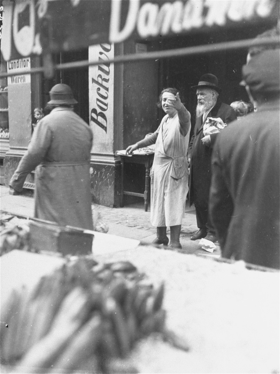 A Jewish female shopkeeper beckons to people on the street in the Berlin Jewish quarter.