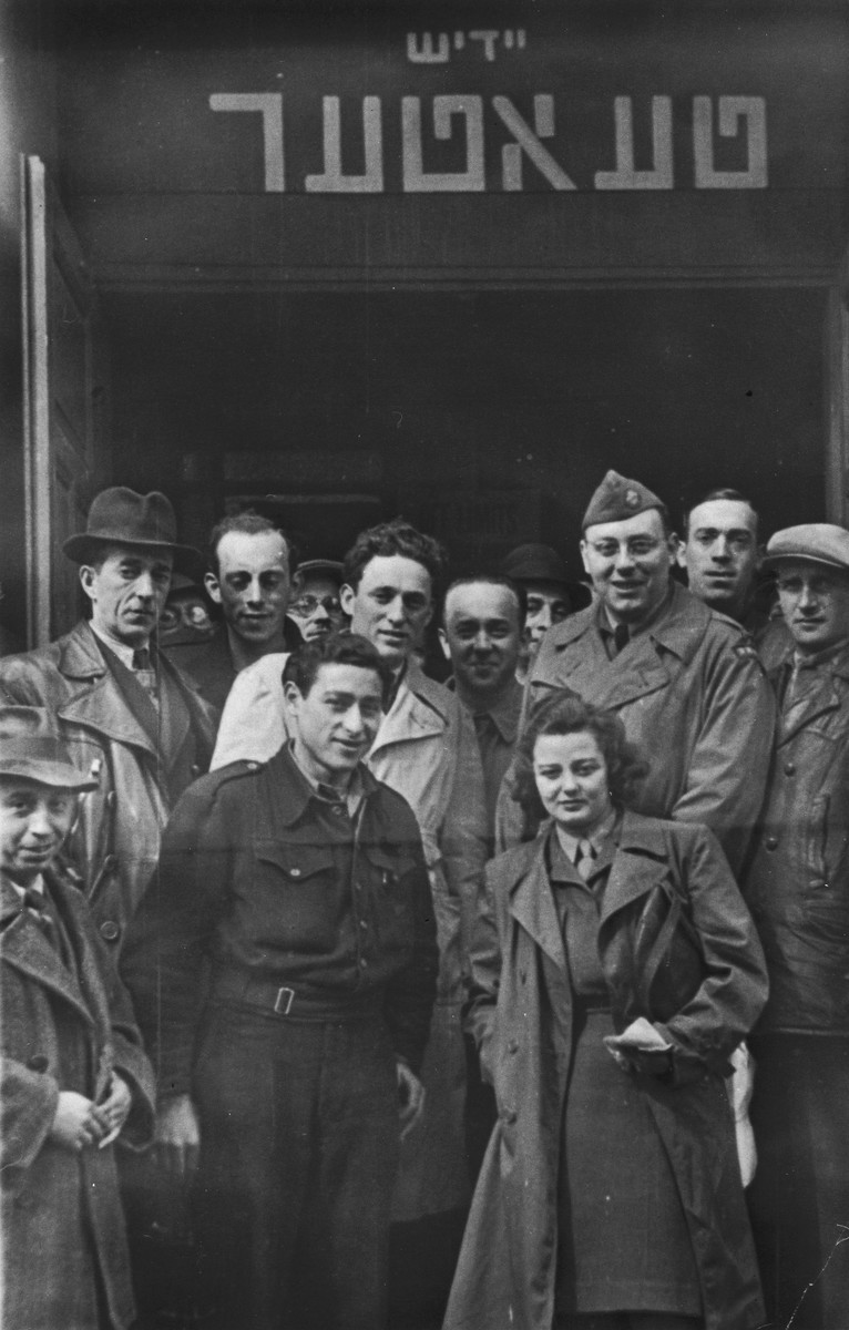 Jewish DPs pose at the entrance to the Yiddish theater in the Lampertheim displaced persons camp.

Among those pictured is Izak Lachter (center, wearing the light trench coat).
