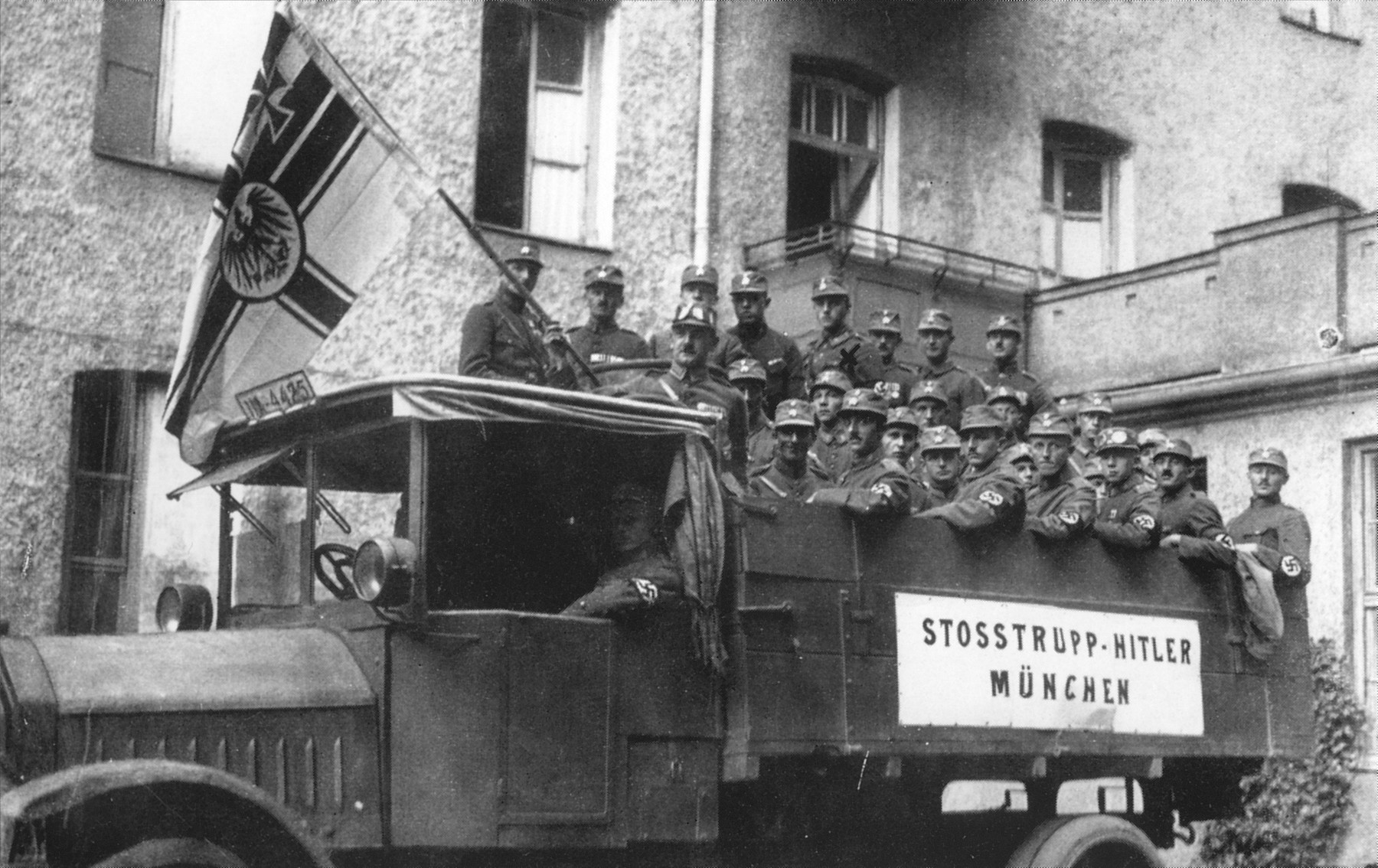 Members of the "Adolf Hitler" SA unit pose on the back of a truck just prior to their departure for Bayreuth to participate in the annual "German Day" celebration.  One of them holds the old Imperial German flag.