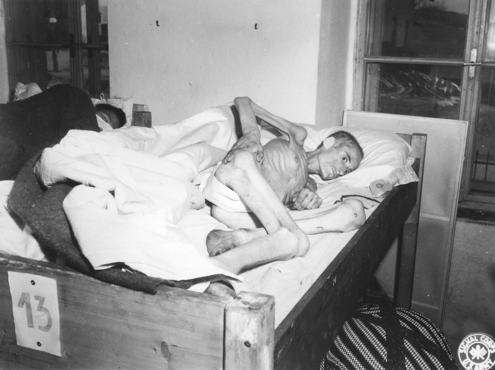 An emaciated female Jewish survivor of a death march lies in an American military field hospital in Volary, Czechoslovakia.

Pictured is twenty-four year old Roszi Frank.