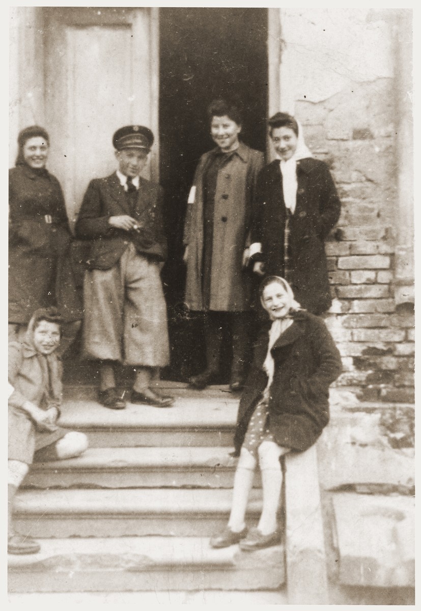 Hana Goldman (seated on the left) with a group of Jewish youth, wearing armbands, poses at the back entrance to the Goldmans' home in the Zabno ghetto.

Her sister Rachela is standing second from the right.