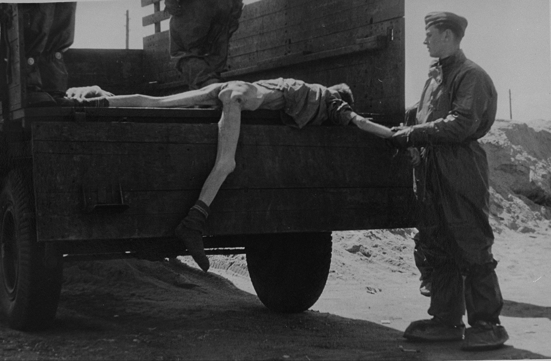 British troops clothed in protective suits unload corpses from a truck.