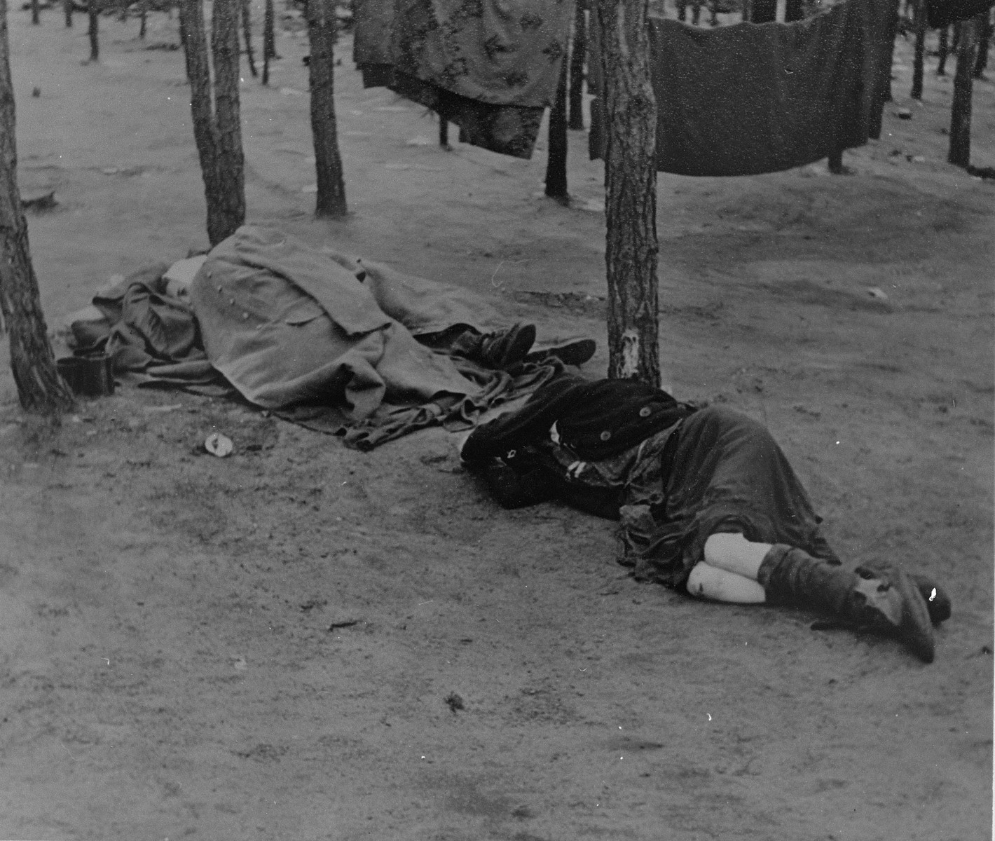 Survivors rest on the ground of Bergen-Belsen after liberation.