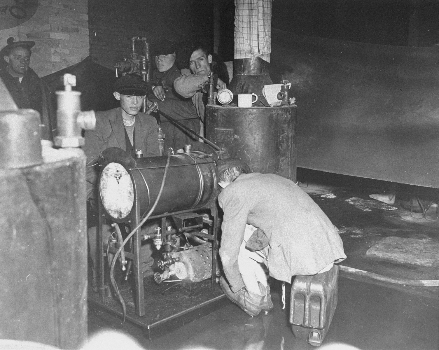 Survivors in Bergen-Belsen warming themselves next to a water heater.

Original caption reads: " In former German prison camp at Belsen, Germany, foreign workers attempt to warm their skeleton like bodies by a water heater.  The camp has no means of heating at all."