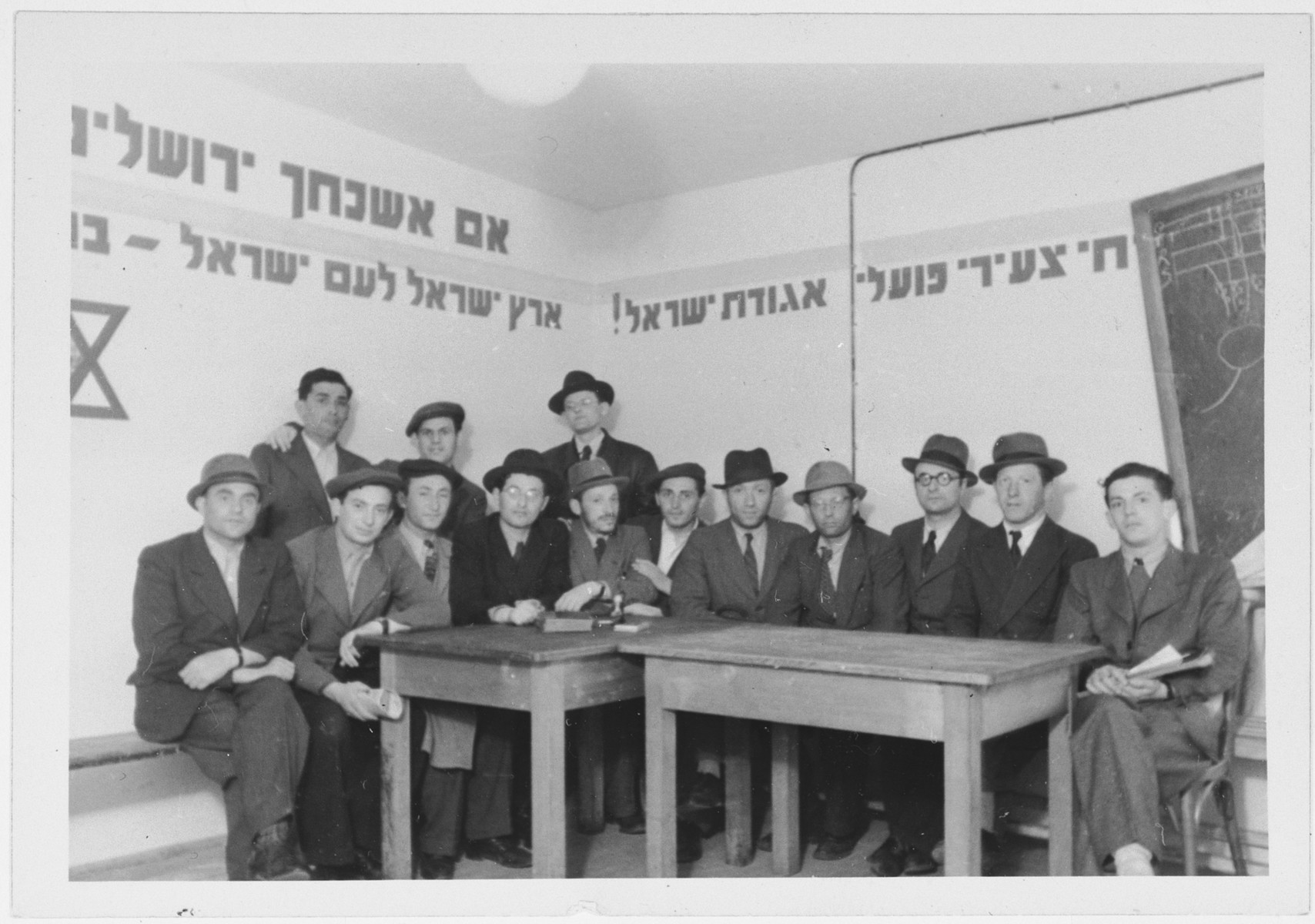 Meeting of religious Zionists in the Zeilsheim displaced persons' camp.

The walls are decorated with sayings including "If I forget thee O Jerusalem" and "the Land of Israel for the People of Israel".