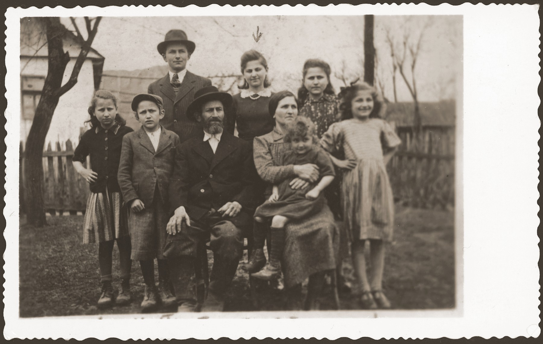 Group portrait of members of a Jewish family in the yard of their home in Volovec.  

Pictured are members of the Kreisman family.  Frida Kreisman is in the back row, center.