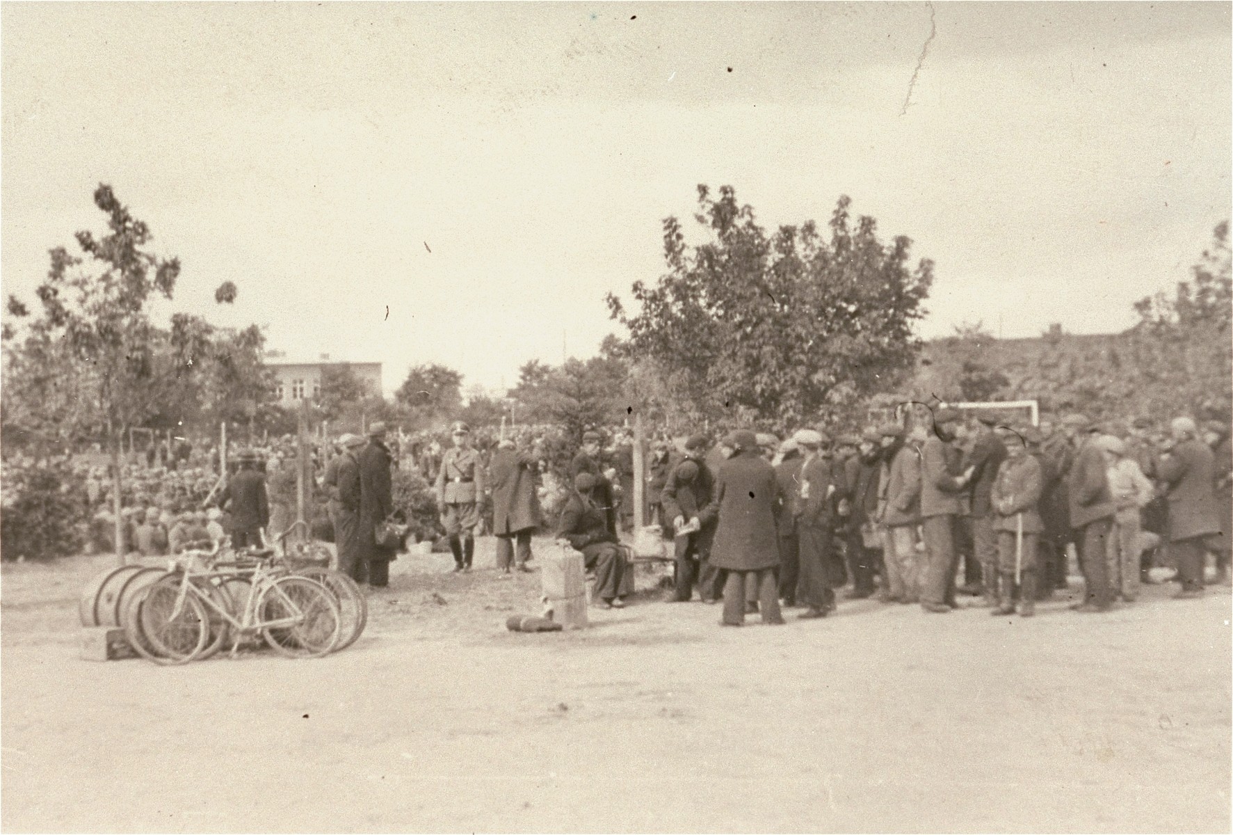 [Probably, an SD officer walking among Polish and Jewish civilians interned in a temporary holding center.]

These prisoners may be what the Germans called "Wehrfaehige", or persons capable of carrying arms, who were summarily interned during and immediately after the Polish campaign as a security measure. 

One image of Einsatzgruppen activities in Poland in 1939, found by Joseph Igra after the war, in a an album in an apartment in Sosnowiec.