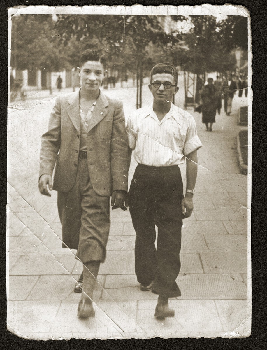 Two Jewish teenage boys walk along a street in Bedzin, Poland.

Pictured are Jakob Fiszel and a friend. Jakob was a student at the Stadler school in Bedzin.
