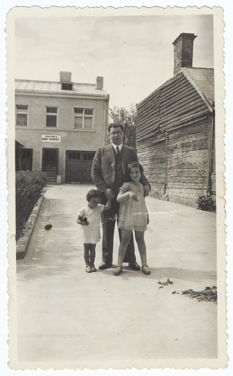 A Jewish father stands with his two daughters in the courtyard of their home.

Pictured are Rina, Gedalyahu and Aviva Ilgovsky.