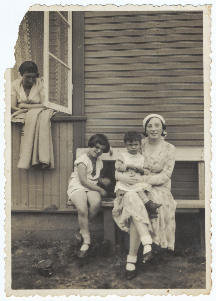 A Lithuanian-Jewish family poses on a wooden bench outside a summer home on the outskirts of Kaunas.

Rina Ilgovsky is sitting on her cousin's lap.  Her mother Hadassah Ilgovsky is looking out the window.